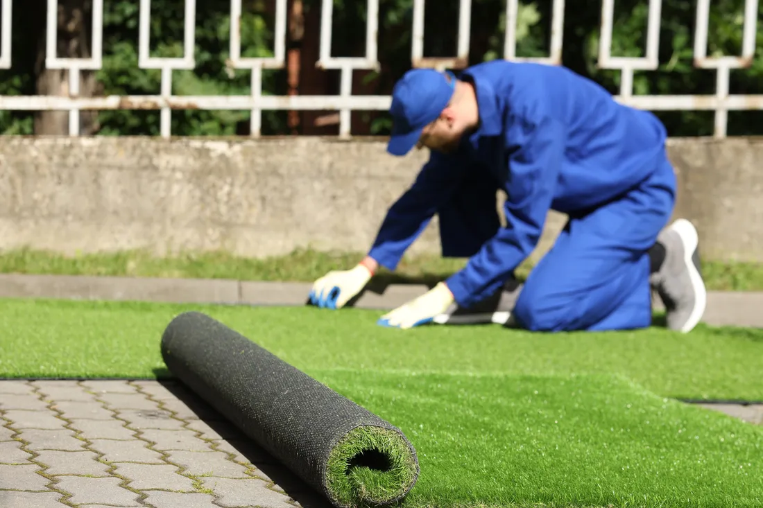 Artificial turf being rolled out during a residential lawn installation