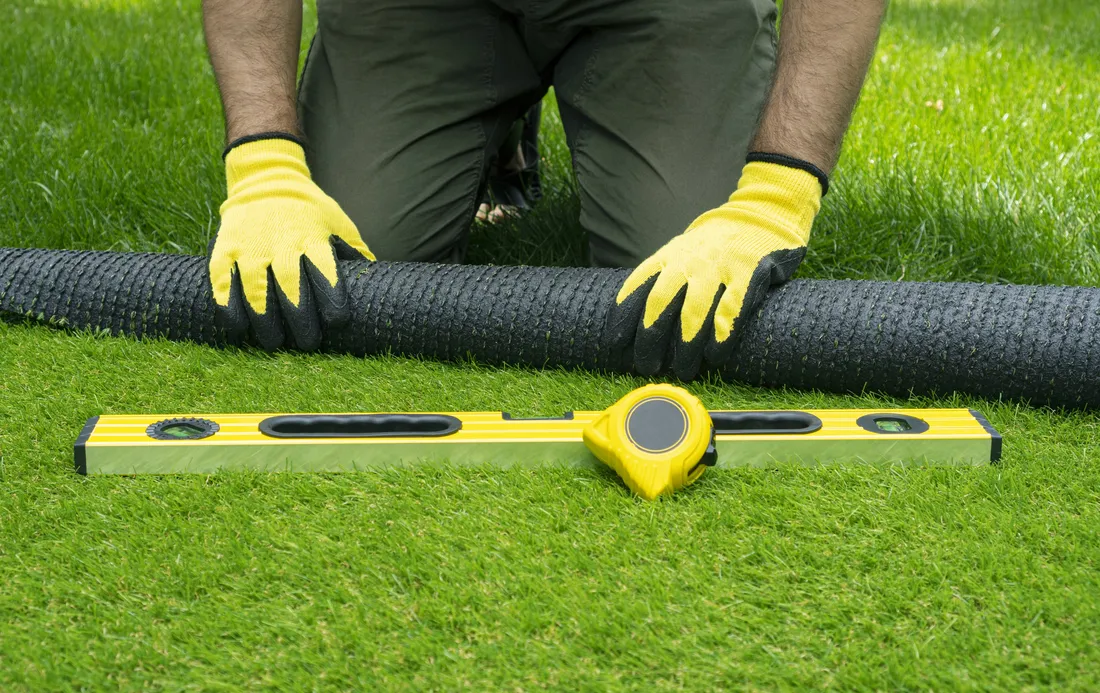 Installer measuring and levelling during an artificial turf installation