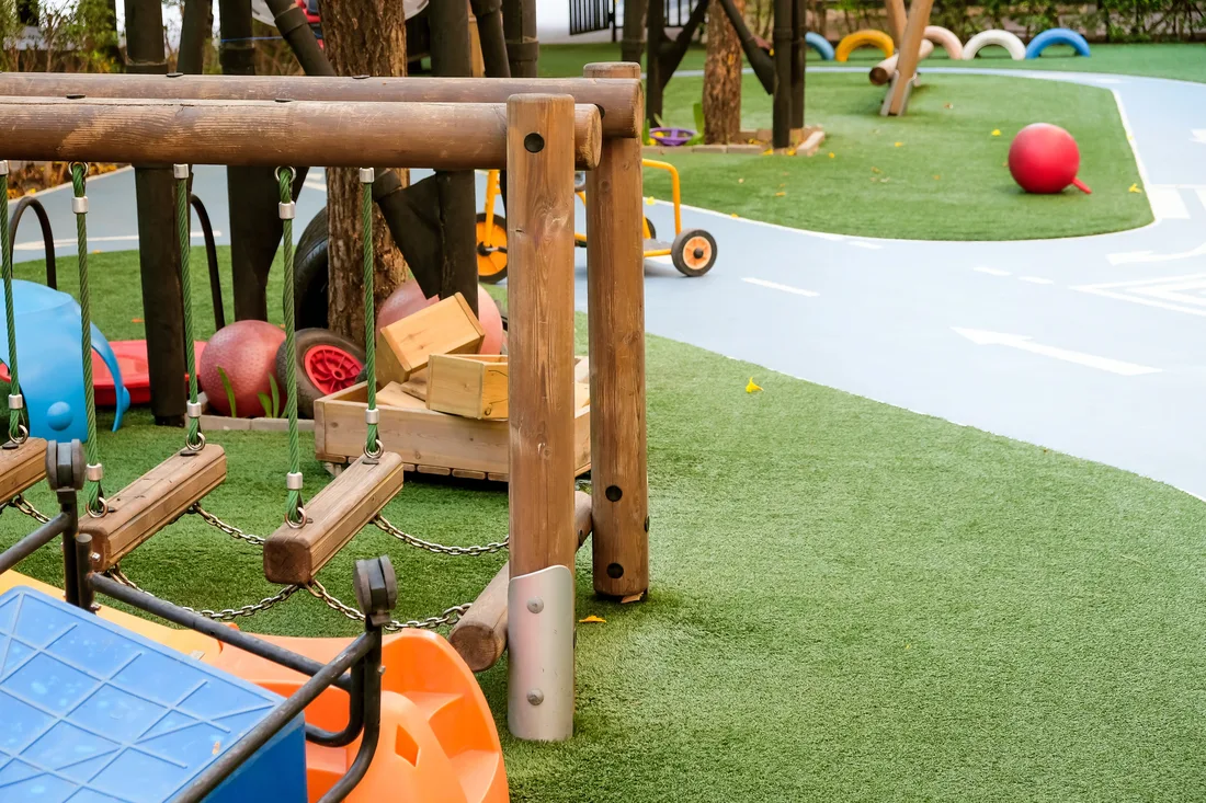 Play equipment and balls on synthetic turf at a childcare-style playground